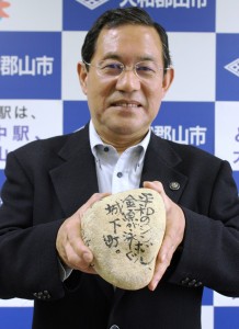 墨と筆で思いを書いた「裏込め石」を手にする上田清市長
