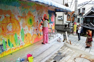 大きなキャンバスに絵を描く作家の様子を写真におさめる来場者らもいた