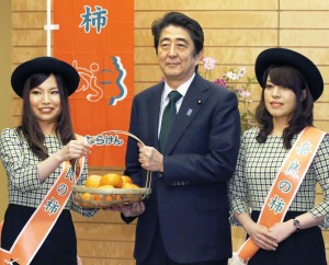 「奈良の柿ＰＲレディ」の崎山明美さん（左）と山本千鶴子さんから柿を贈られた安倍首相