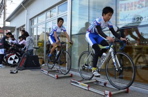 ローラー上で競技用自転車の練習を披露する生徒ら