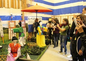 「町家の案山子巡り」のメーン会場に展示されたかかしにカメラを向けるフランスの高校生ら