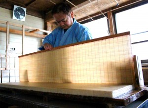 紙床に漉いた和紙を重ねる福西正行さん