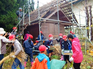 氷室の屋根から降ろしたわらを運ぶ児童