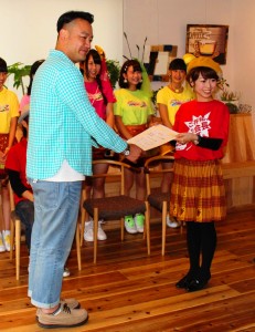 西日本ハンバーガー協会の松井香奈会長から任命証を受け取るたむらけんじさん