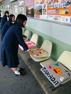 座布団をホームのベンチに設置する生徒