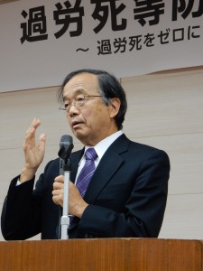 シンポジウムで講演する松丸正弁護士