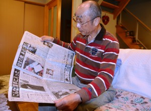 容疑者逮捕の翌日の朝刊を手に取る葛本英治さん