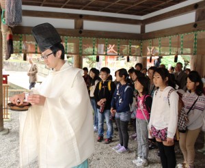 奉納された菜種油で灯明皿に明かりを灯す神職
