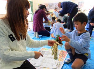 2人で協力してしめ縄に飾りを付ける親子
