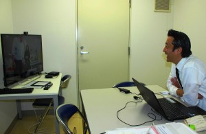 テレビ会議システムを使って大阪の支社にいる社員とやり取りをする塩沢さん（右）