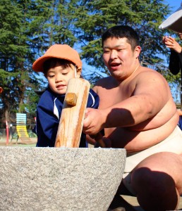 相撲部員の助けを借りて餅をつく園児