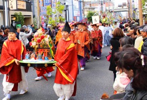 田楽座の行列先頭で花笠を持つ浜川記者（右）