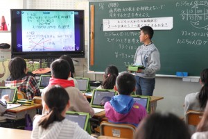 自分のノートをモニターに映し、宿題を解いた方法を説明する児童