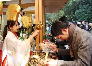 福を授けるために参拝者に向かって鈴を鳴らす福娘