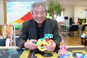 ラキューで作られた恐竜を手にする吉條宏社長