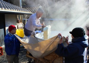 タンクから蒸した米を取り出すメンバー