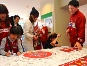 メッセージを書き込む観客と辻屋健選手（右）