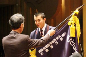 中川敏男校長から紺色の選抜旗を受け取る野球部の岡沢智基主将