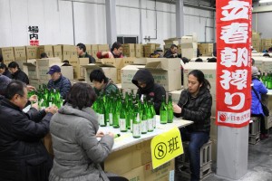 立春朝搾りの酒にラベルを貼る酒販店関係者ら