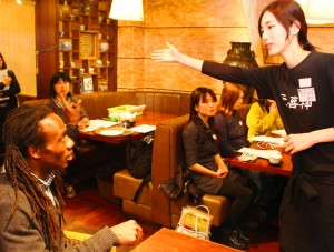 英語での接客練習に取り組む参加者を指導するニクソンさん（左）