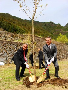 ヤマザクラを植樹する栗山忠昭村長（左）と菊池攻社長