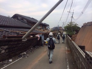 熊本県益城町で活動する判定士。電柱が大きく傾き、地震の激しさを物語っている＝２３日（県提供）