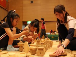 河原の小石のような「まあるいつみき」でドミノ倒しを作って遊ぶ子供たち