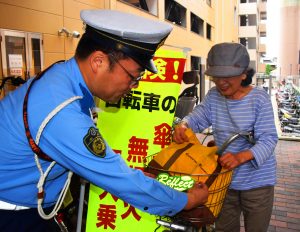 自転車利用者に反射材を配布し、安全利用を呼びかける生駒署員