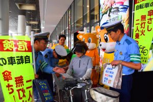 自転車利用者に反射材を配布し、安全利用を呼びかける生駒署員