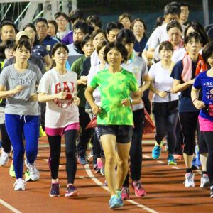 参加者と競技場を走る講師の佐藤光子さん(中央)