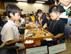 真剣な表情で対局する川西町立川西小の選手（右）