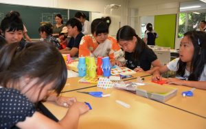学生の指導を受けながら折り紙で短冊や七夕飾りなど作る児童