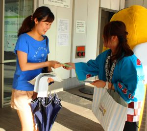 選挙管理委員やめいすいくんが通行人に割りばしを渡し投票を呼びかけた