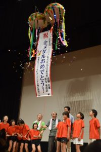 「タカマツ」ペアの金メダル獲得を祝ってくす玉を割る父、昭博さん(中央)ら