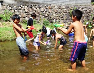 日差しの下、川で水遊びを楽しむ子供たち