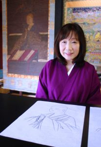 中将姫の写仏下絵を前に話す久保田聖美さん。左奥は県文化財の中将姫画像
