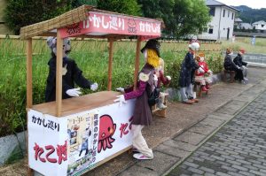 屋台でたこ焼きを売る案山子も