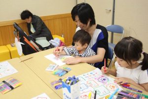 家族連れが集まってプラスチックにイヌやネコのイラストを描いて名札を作っていた