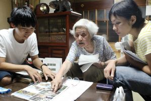 アルバムや日記帳を開きながら、前川さん（中央）の経験を聞き取るメンバーら