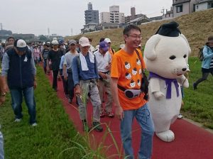 雪丸と一緒に大和川の河川敷を歩く参加者ら