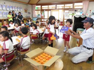 園児に天理産の柿「刀根早生」をプレゼントする野口哲男さん(右)