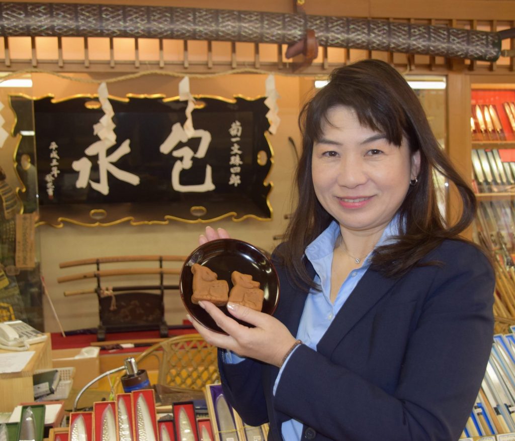 春日鹿まんじゅう〈かのこ〉を手にする菊一文珠四郎包永社長の柳澤育代さん
