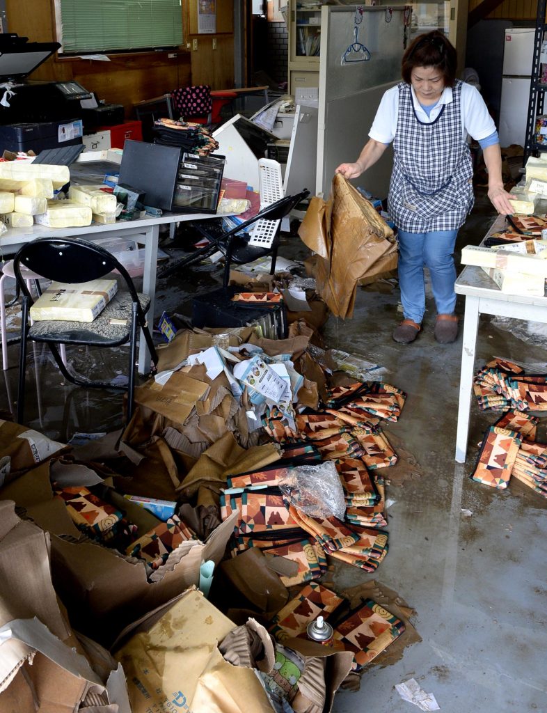 浸水した事務所の後片付けに追われる従業員ら=23日午前、奈良県三郷町(水島啓輔撮影)